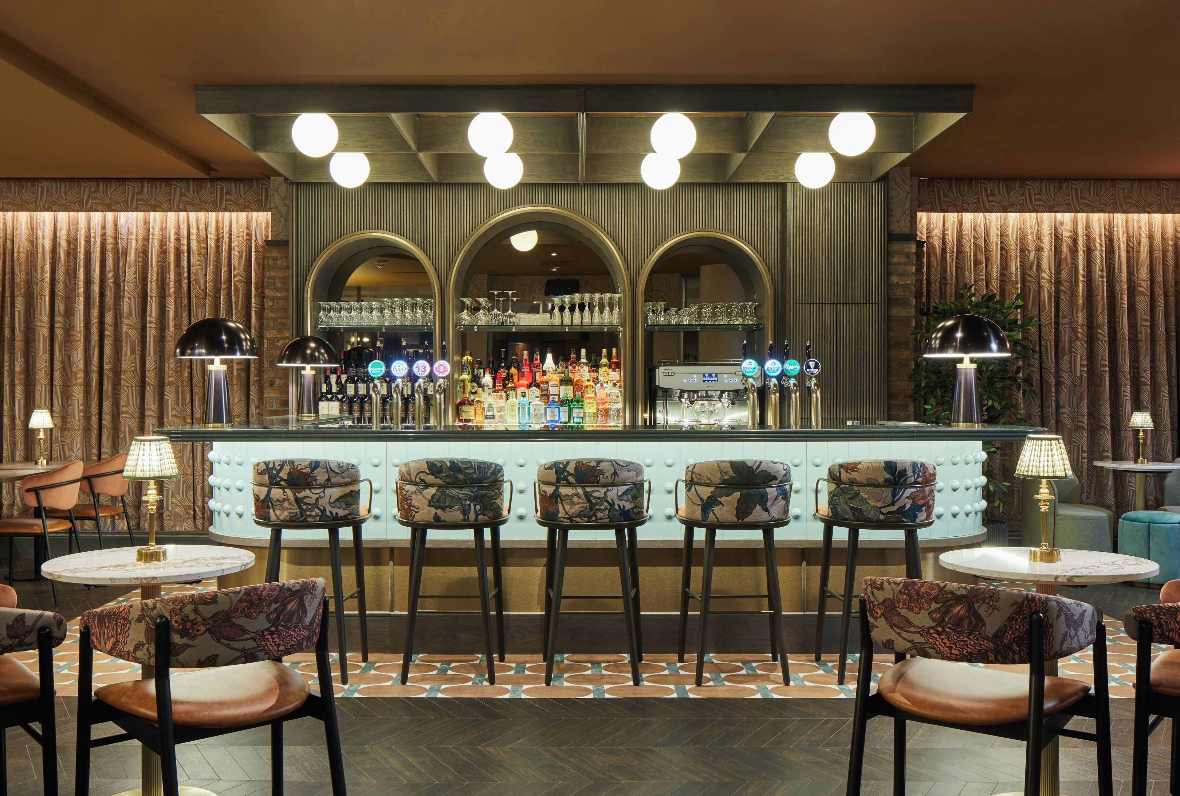 A bar area with a counter, bar stools, and a selection of bottles.