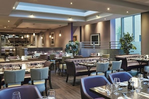 A modern restaurant with high ceilings, pendant lighting, and a view of the city. - Leonardo Hotel Dublin Parnell Street (Dublin)