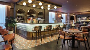 A bar area with a counter, stools, and a seating area with tables and chairs. - Leonardo Hotel Dublin Parnell Street (Dublin)