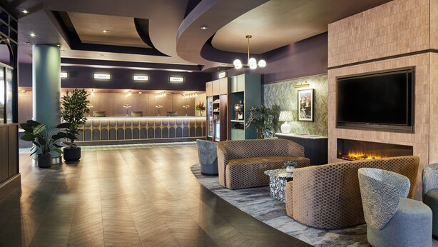 A spacious lobby with a reception desk, seating area, and a large flat-screen TV mounted on the wall. - Leonardo Hotel Dublin Parnell Street (Dublin)