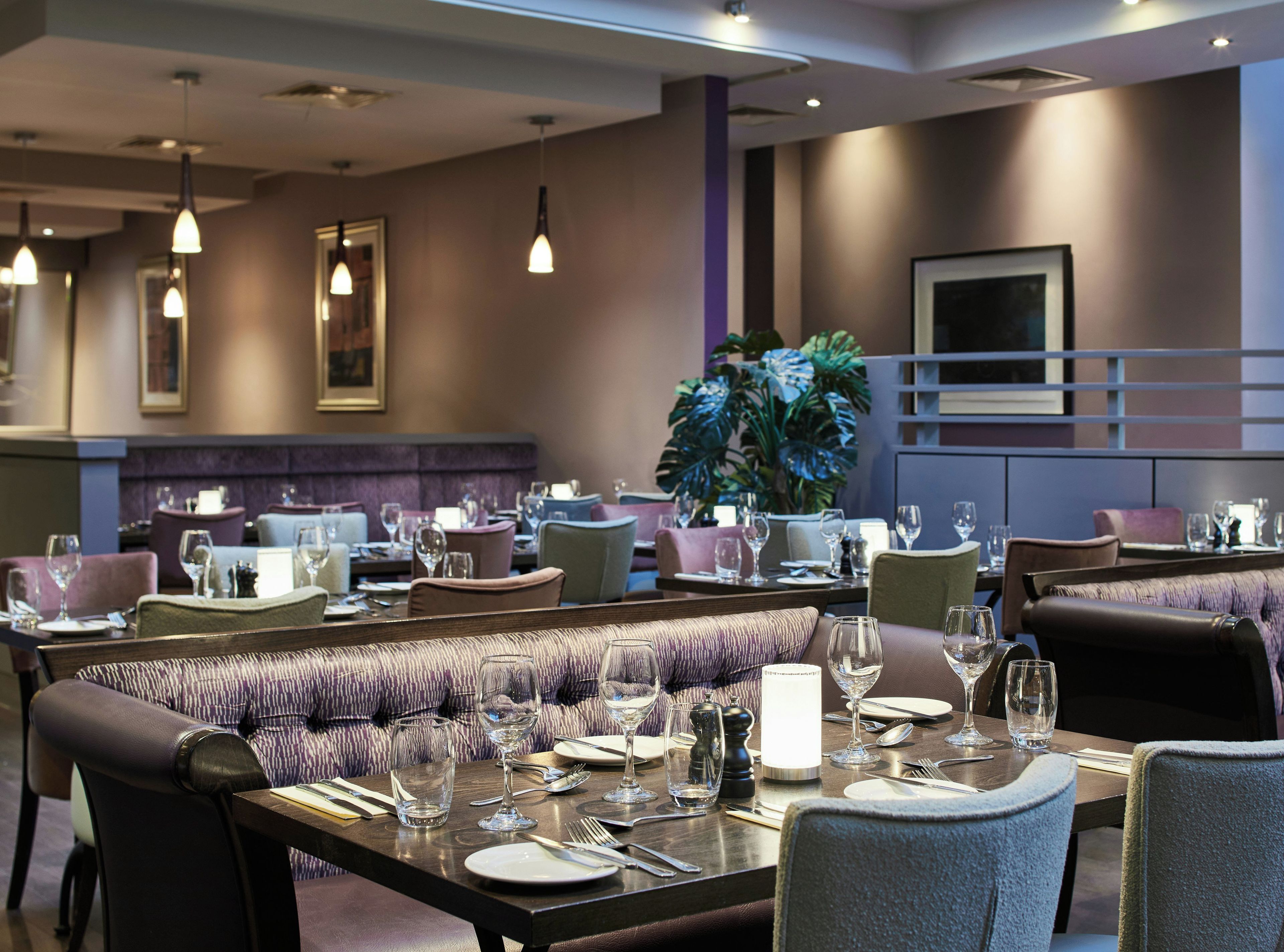 A restaurant with a long dining table set for a meal, surrounded by cushioned seating.
