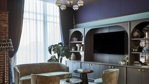 A modern living room with a sofa, armchair, and coffee table, a flat-screen TV, and a bookshelf. - Leonardo Hotel Dublin Parnell Street (Dublin)