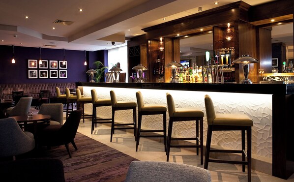 A bar area with a counter, bar stools, and a seating area with tables and chairs. - Leonardo Hotel Dublin Parnell Street (Dublin)