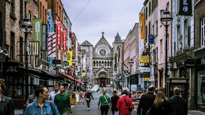 Une rue bordée de divers commerces et une église imposante dotée d’un clocher.