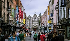 A street lined with various shops and a prominent church with a clock tower. - Leonardo Hotel Dublin Parnell Street (Dublin)