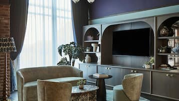 A modern living room with a sofa, armchair, coffee table, and a flat-screen TV mounted on a cabinet.