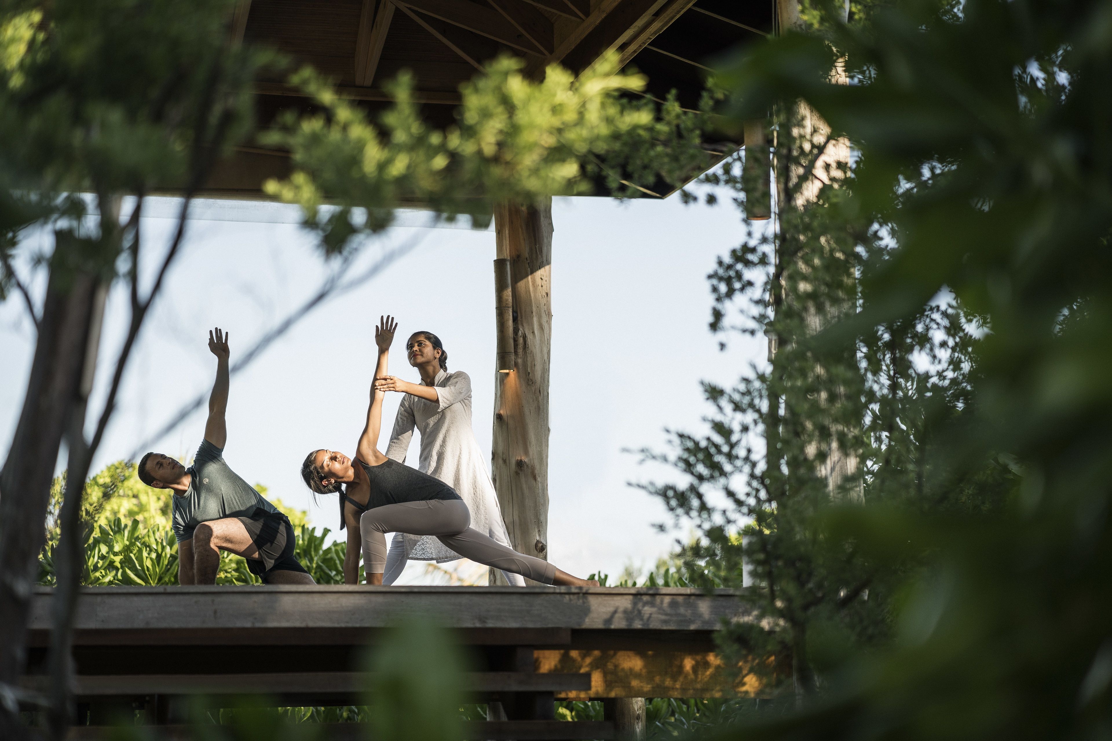 Una terraza de madera con personas practicando yoga.