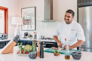 A chef preparing food in a modern kitchen with a stove, cutting board, and various kitchen utensils.