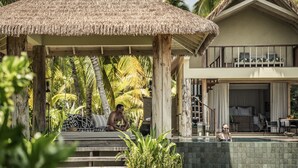 A thatched-roof gazebo, a pool, and a two-story building with a balcony.