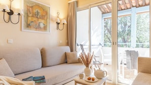 A living room with a sofa, a table with a vase and a book, and a sliding glass door leading to an outdoor area.