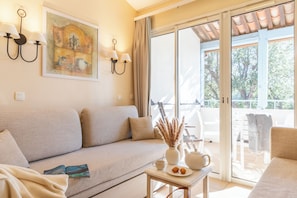 A living room with a sofa, a table with a vase and a book, and a sliding glass door leading to an outdoor area.