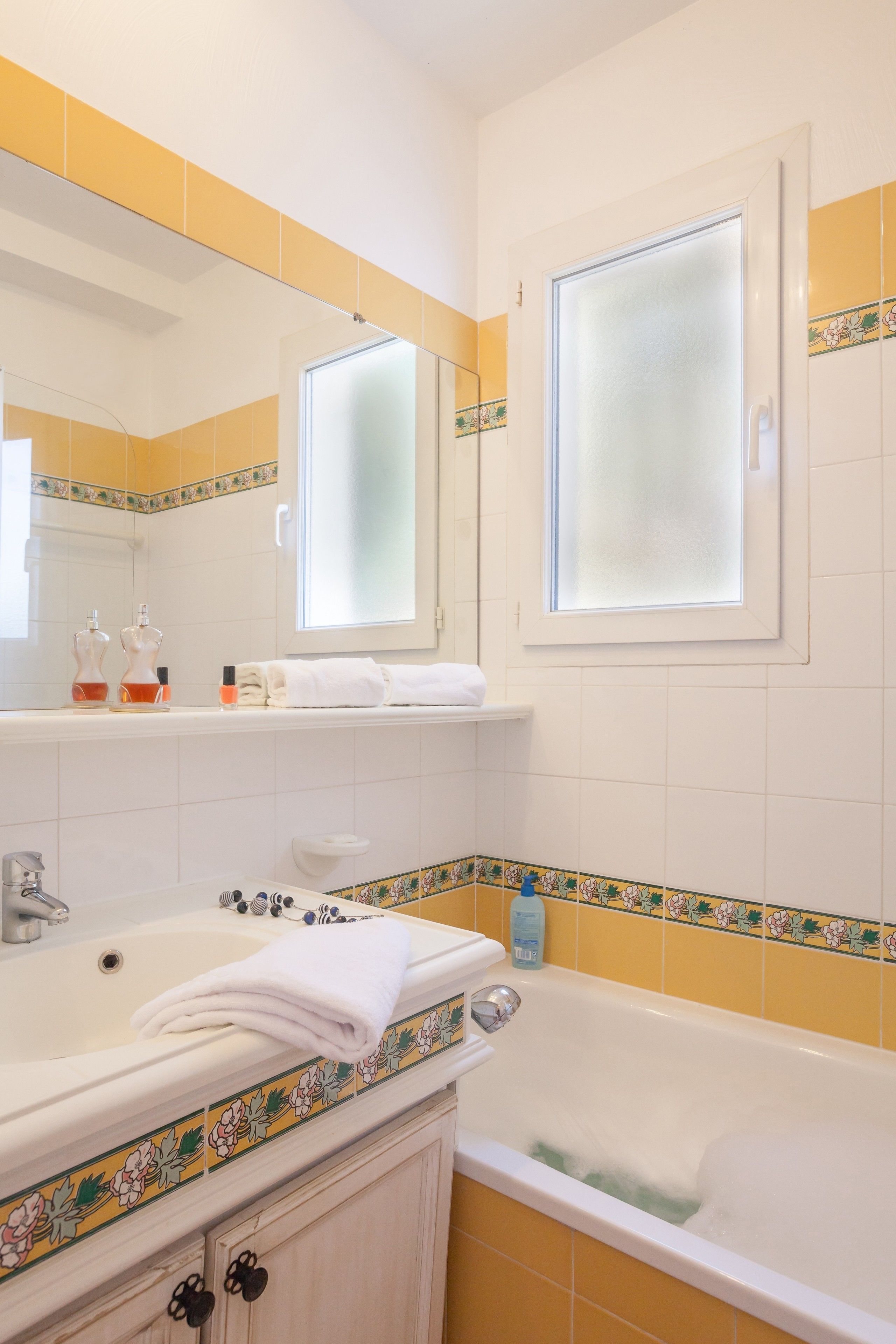 Ein Badezimmer mit Badewanne, Waschbecken, Spiegel und Fenster.