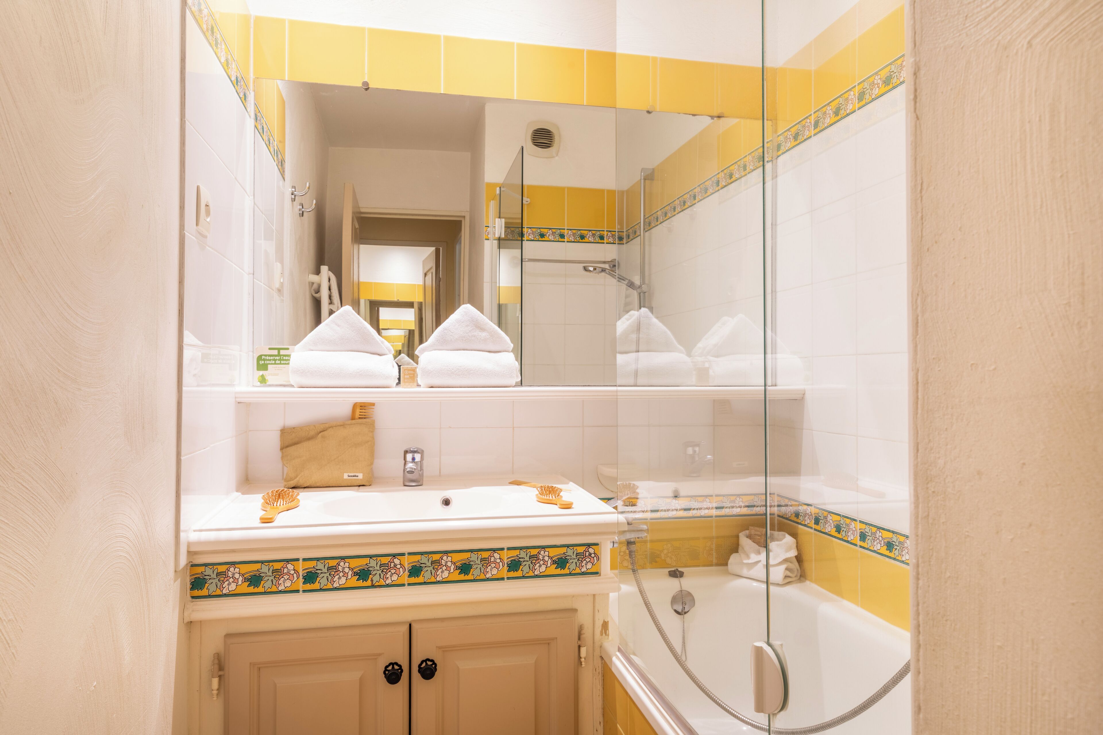 Un baño con cabina de ducha de vidrio, un lavamanos blanco con espejo y un perchero para toallas.