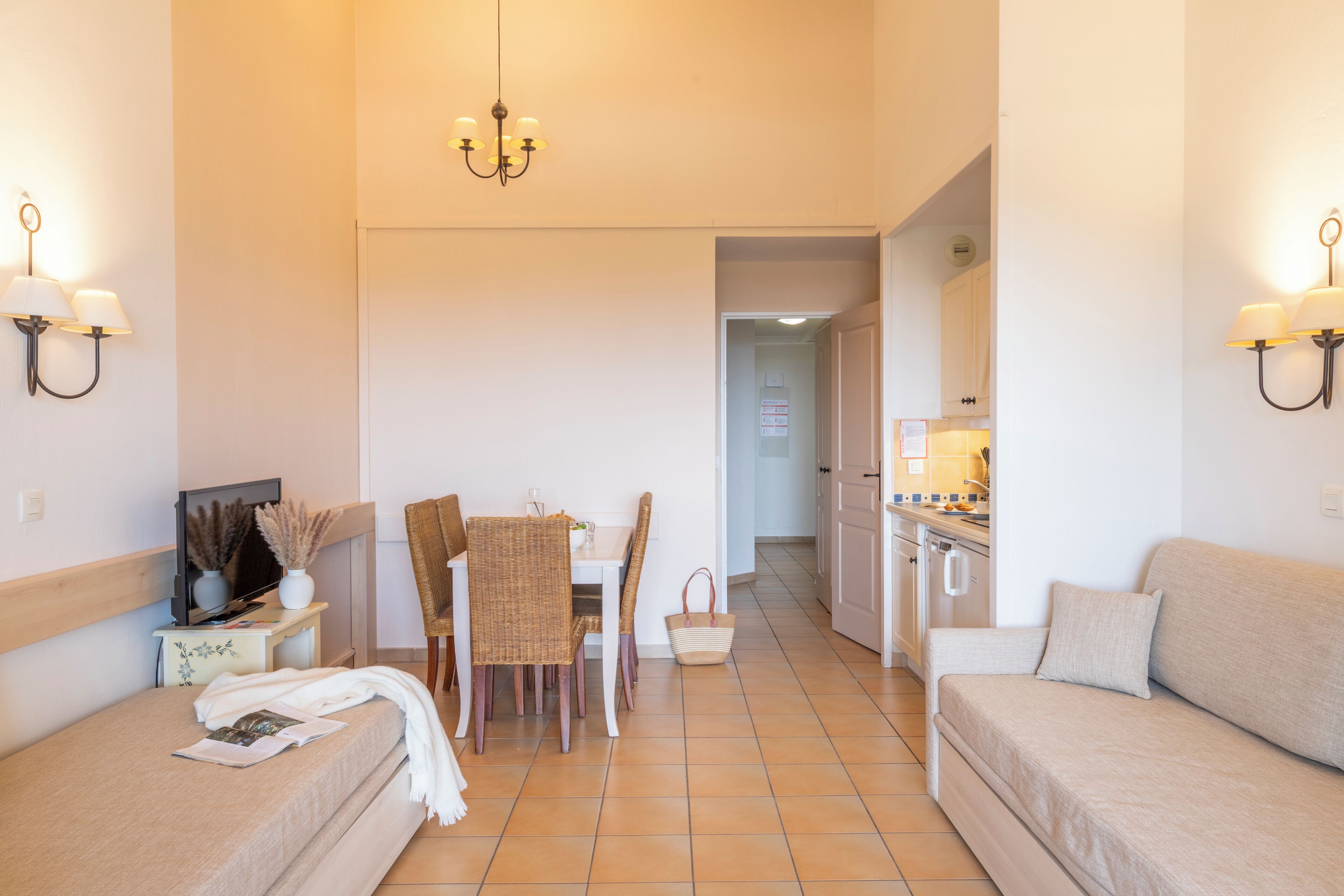 A hotel room with a bed, a dining table with chairs, a kitchenette, and a sofa.