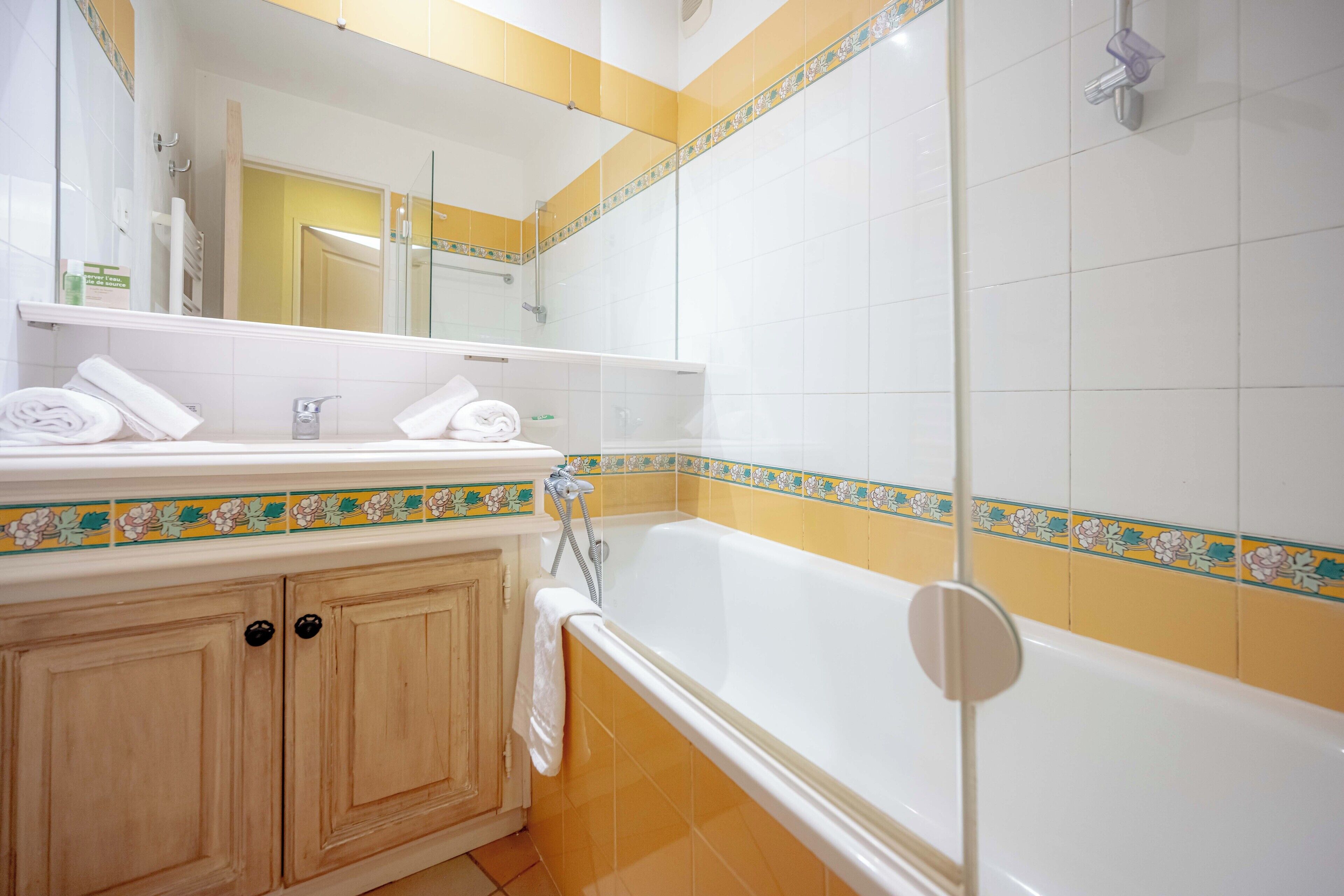 A bathroom with a bathtub, a shower, and a vanity with towels.
