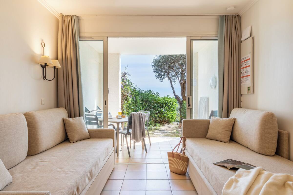 A room with two sofas, a table, and a view of the outdoors.