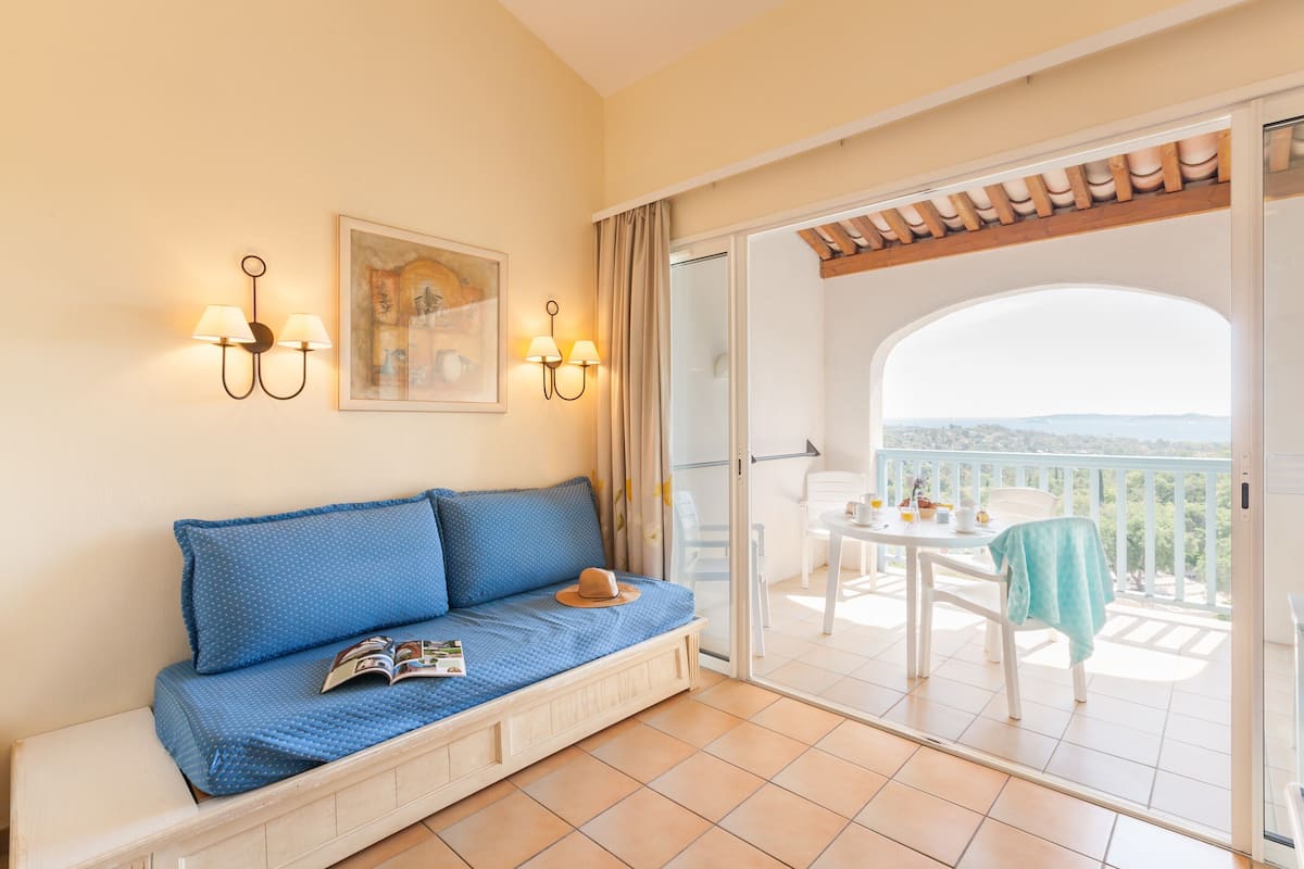 A balcony with a white table, chairs, and a view of the landscape.
