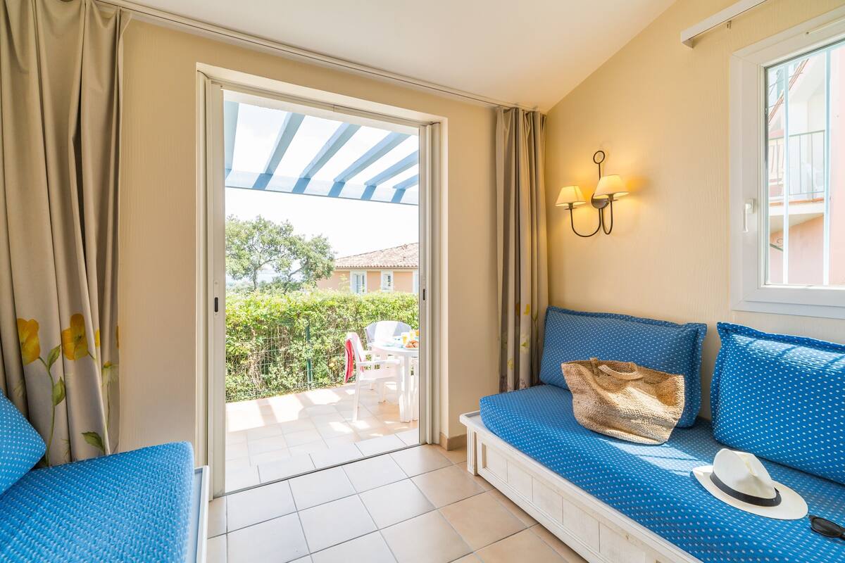 A room with a blue sofa, a white bench, and a window with curtains.