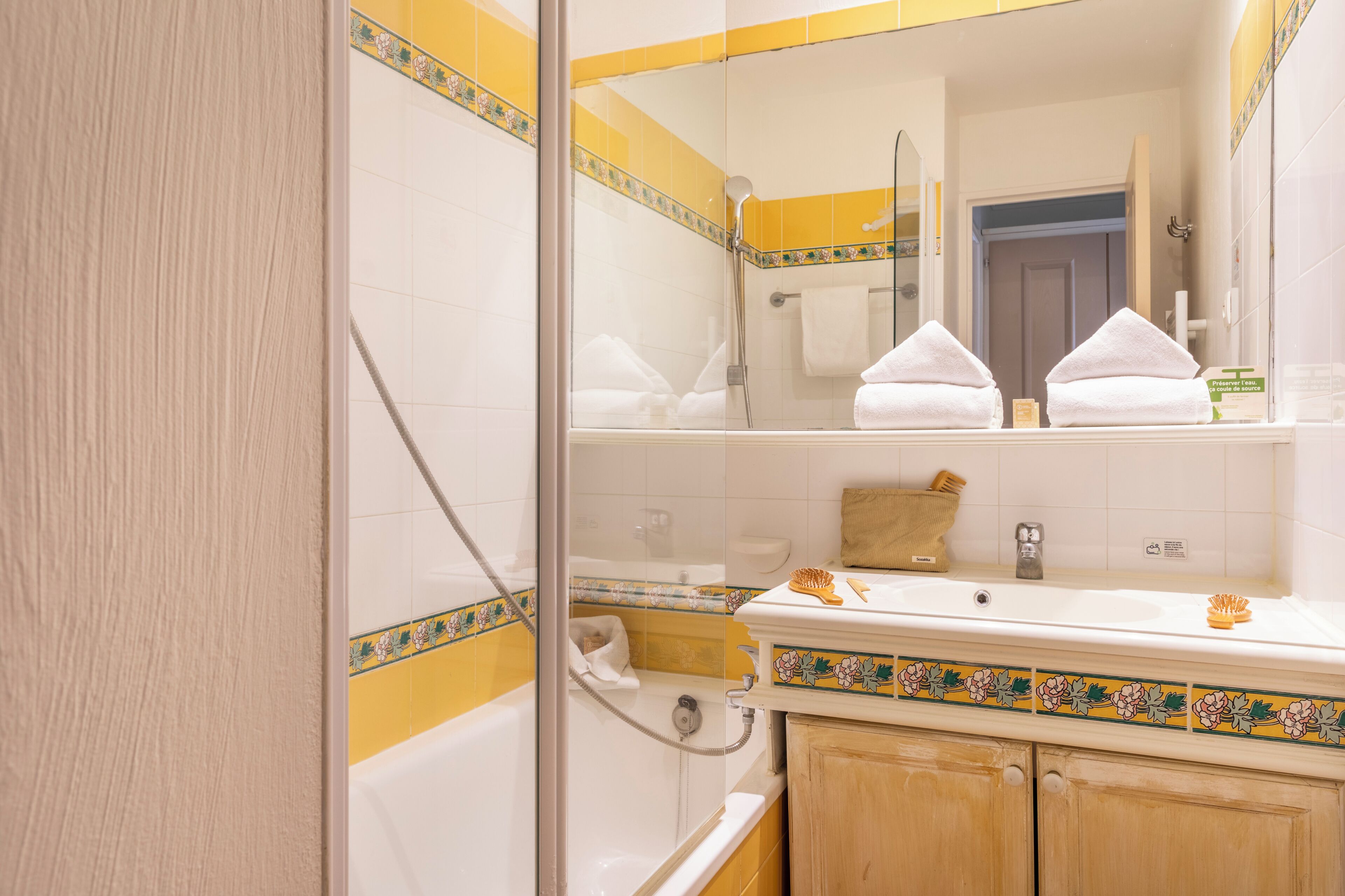 Een badkamer met een douchecabine van glas, een wastafel met spiegel en een handdoekrek.