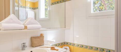 Une salle de bain avec une baignoire, un lavabo, un miroir et une fenêtre.