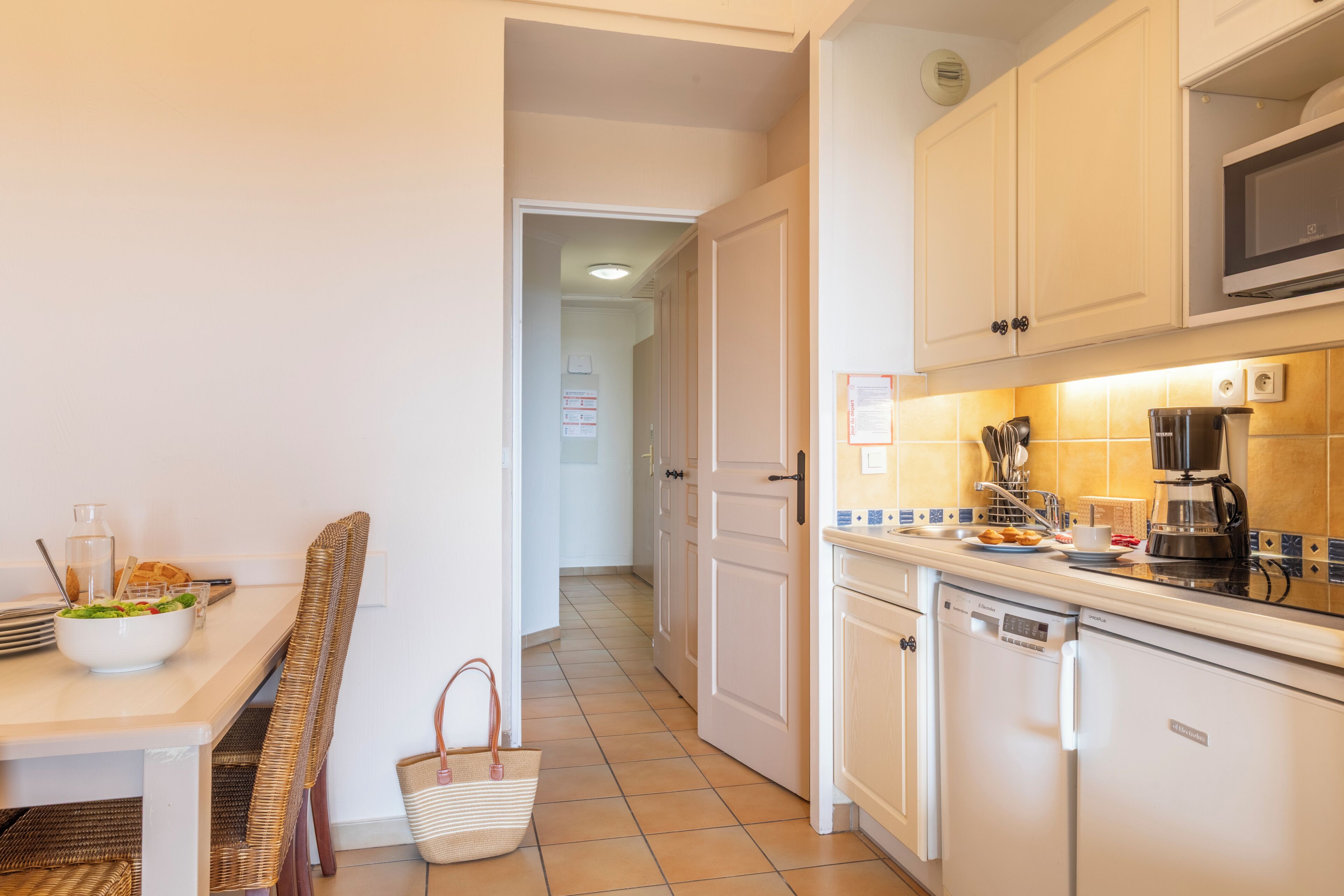 Una cocina con mesa, sillas, microondas, cafetera y lavavajillas.