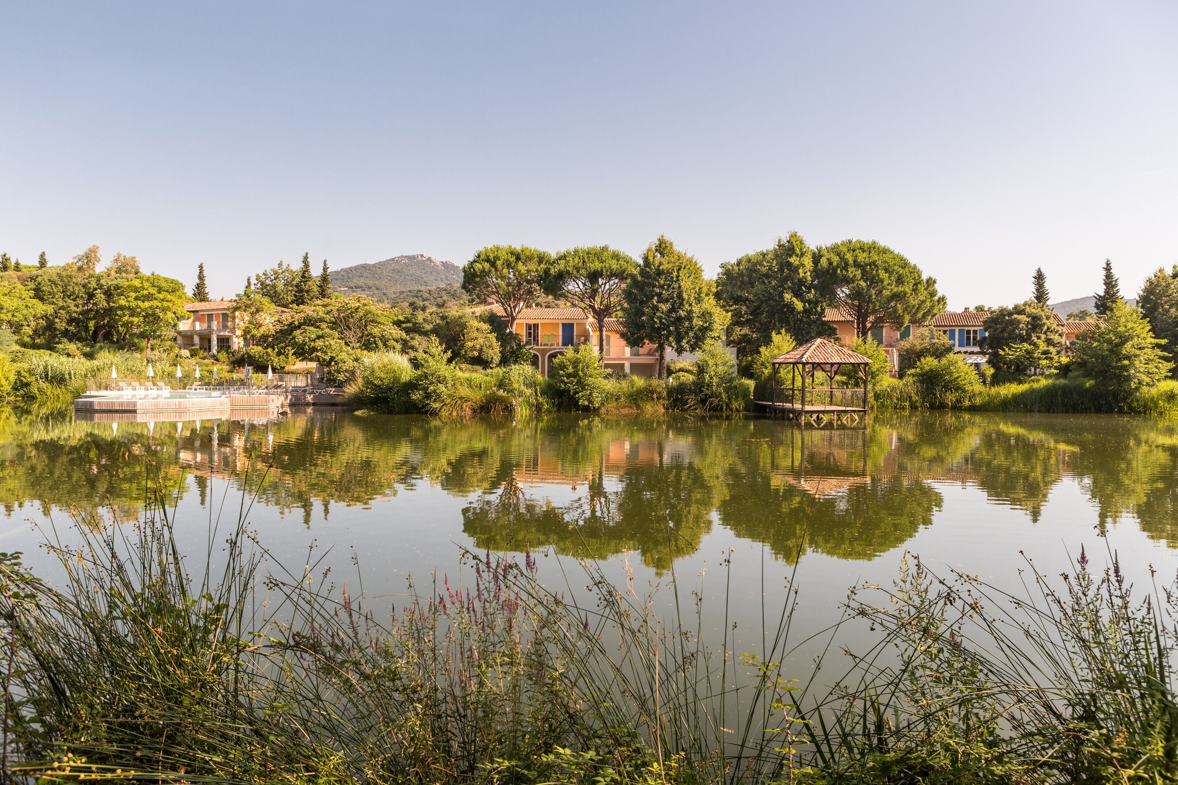 A serene lakeside setting with buildings, trees, and a gazebo.