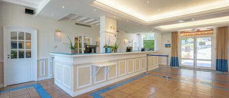 A hotel lobby with a reception desk, a large window, and a door.