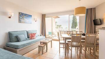 Un salon moderne comprenant un canapé, une table à manger, des chaises et un téléviseur.