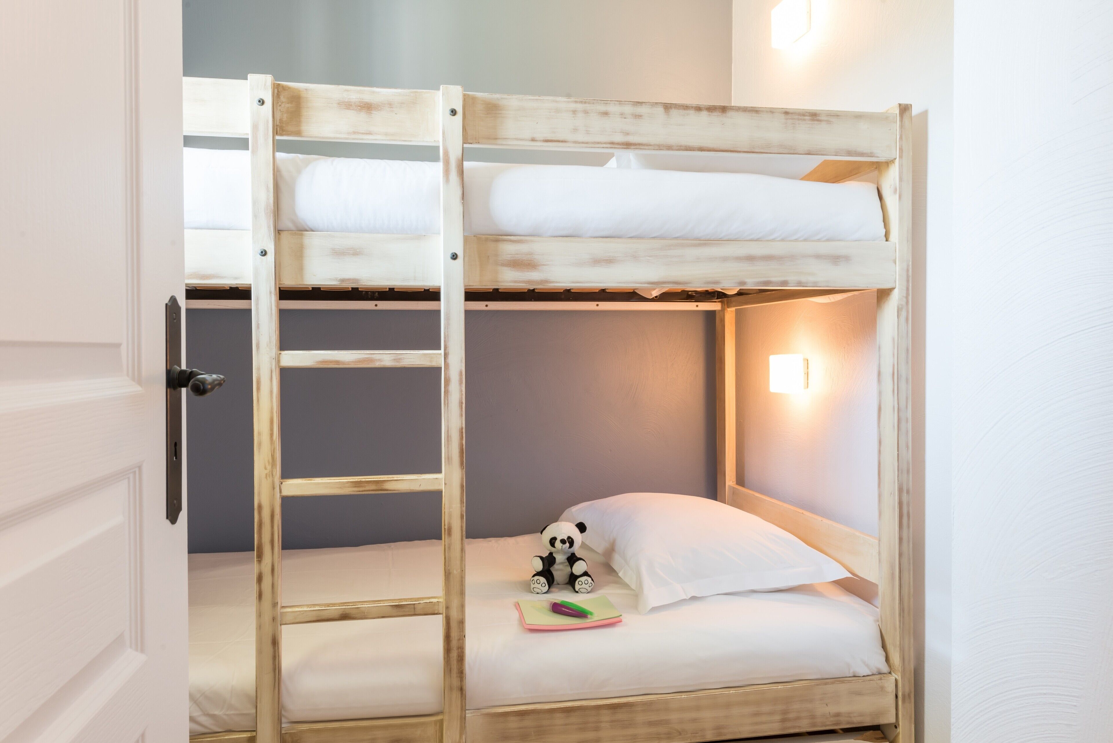 Ein Stockbett mit einer Leiter, ein kleines Panda-Spielzeug und eine Nachttischlampe.