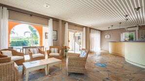 A spacious lobby with wicker furniture, a reception desk, and a view of the outdoors. - Pierre & Vacances Les Rivages des Issambres (Roquebrune-sur-Argens)