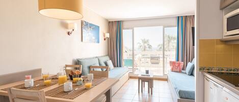A modern hotel room with a dining area, a sofa, and a kitchenette.