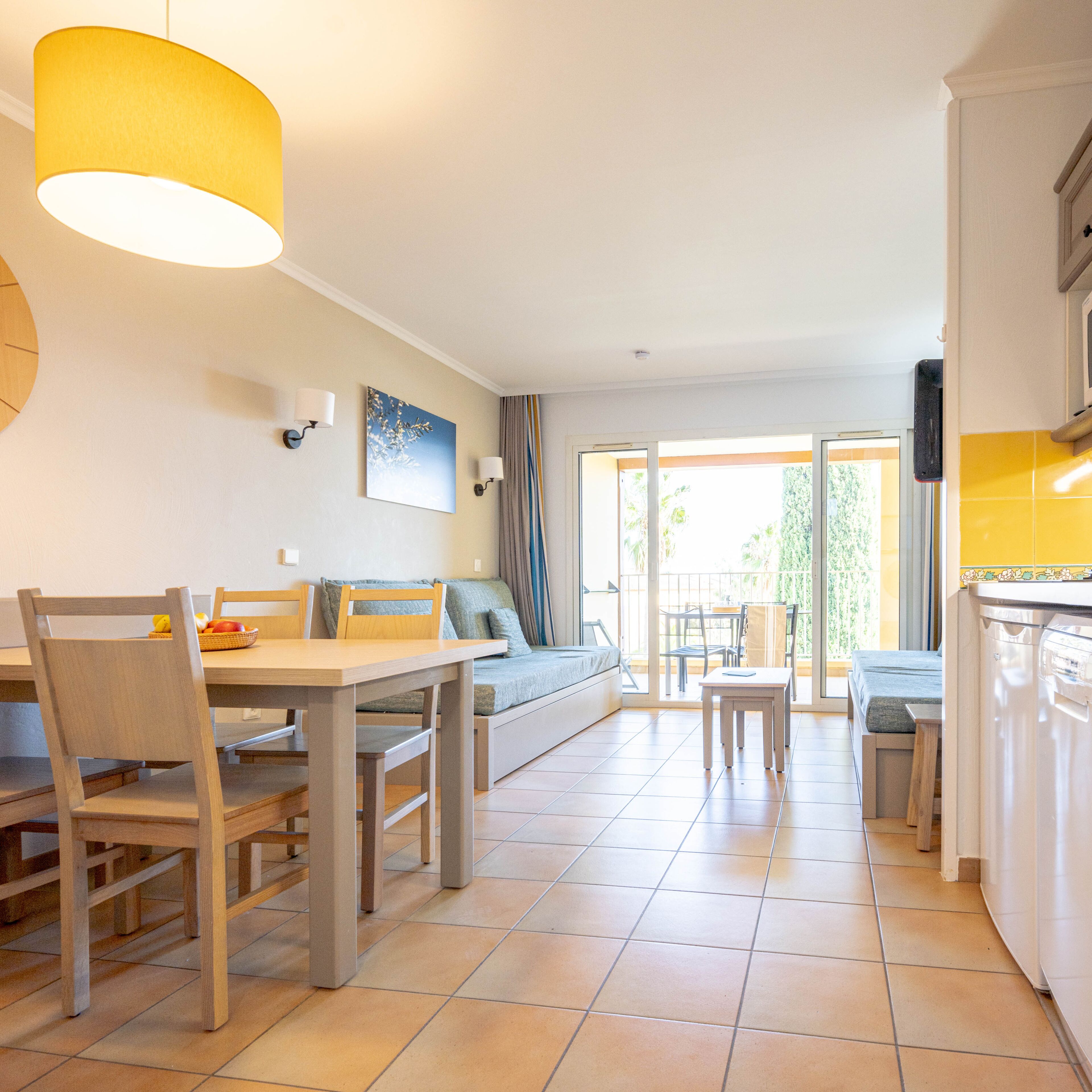 A modern kitchen with a dining area, a sofa, and a view of the outdoors.
