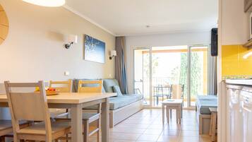 A modern kitchen with a dining area, a sofa, and a view of the outdoors.
