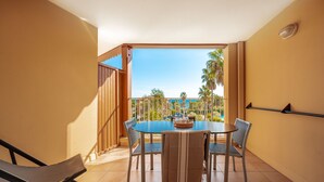 A balcony with a table and chairs, a view of palm trees, and a clear sky. - Pierre & Vacances Les Rivages des Issambres (Roquebrune-sur-Argens)