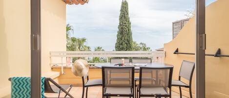 An outdoor patio with a round table and chairs, a towel, and a chair with a towel.