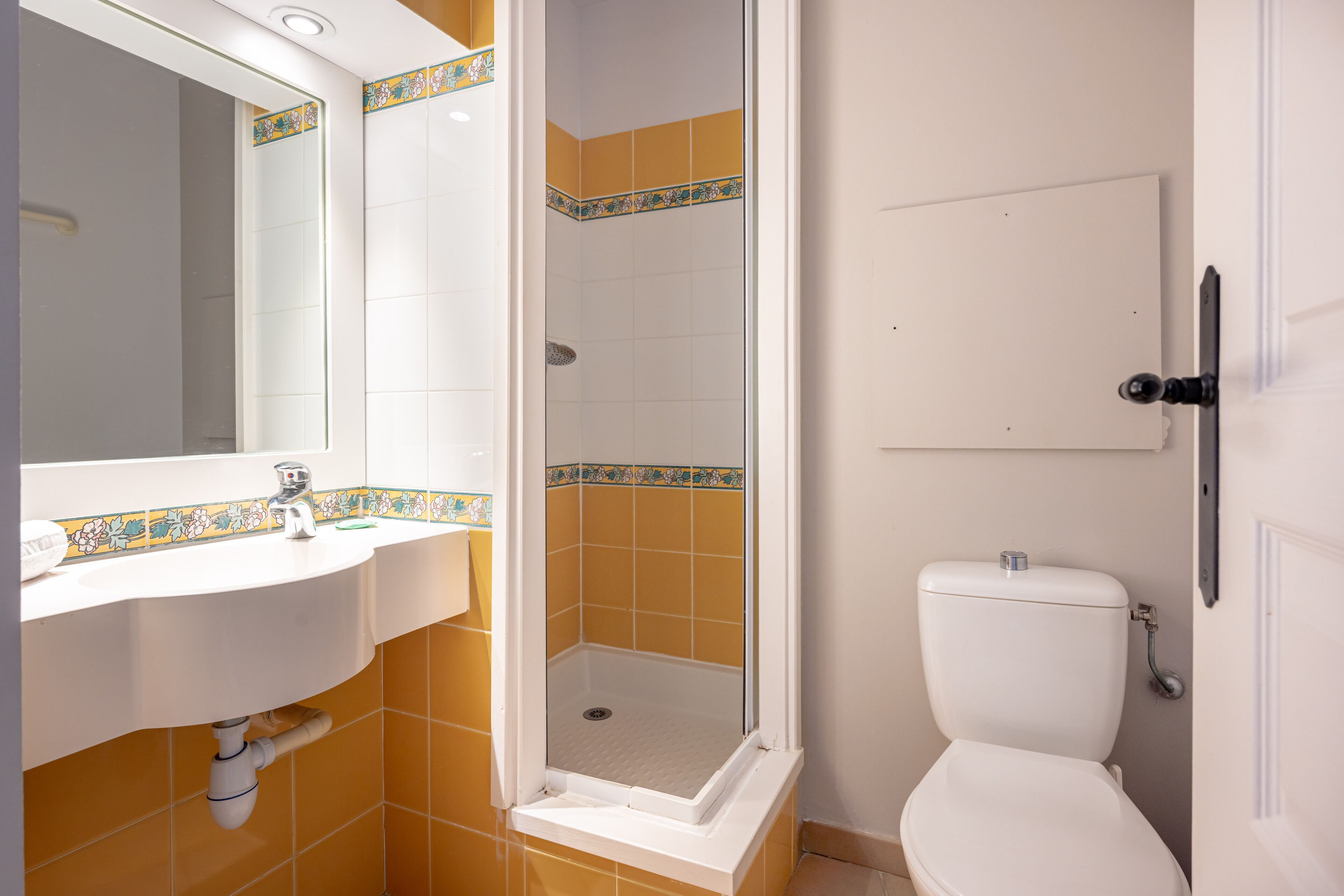 A bathroom with a white sink, a shower enclosure, and a toilet.