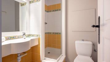 A bathroom with a white sink, a shower enclosure, and a toilet.