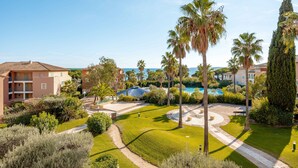 A resort with a pool, palm trees, and a clear view of the sea. - Pierre & Vacances Les Rivages des Issambres (Roquebrune-sur-Argens)