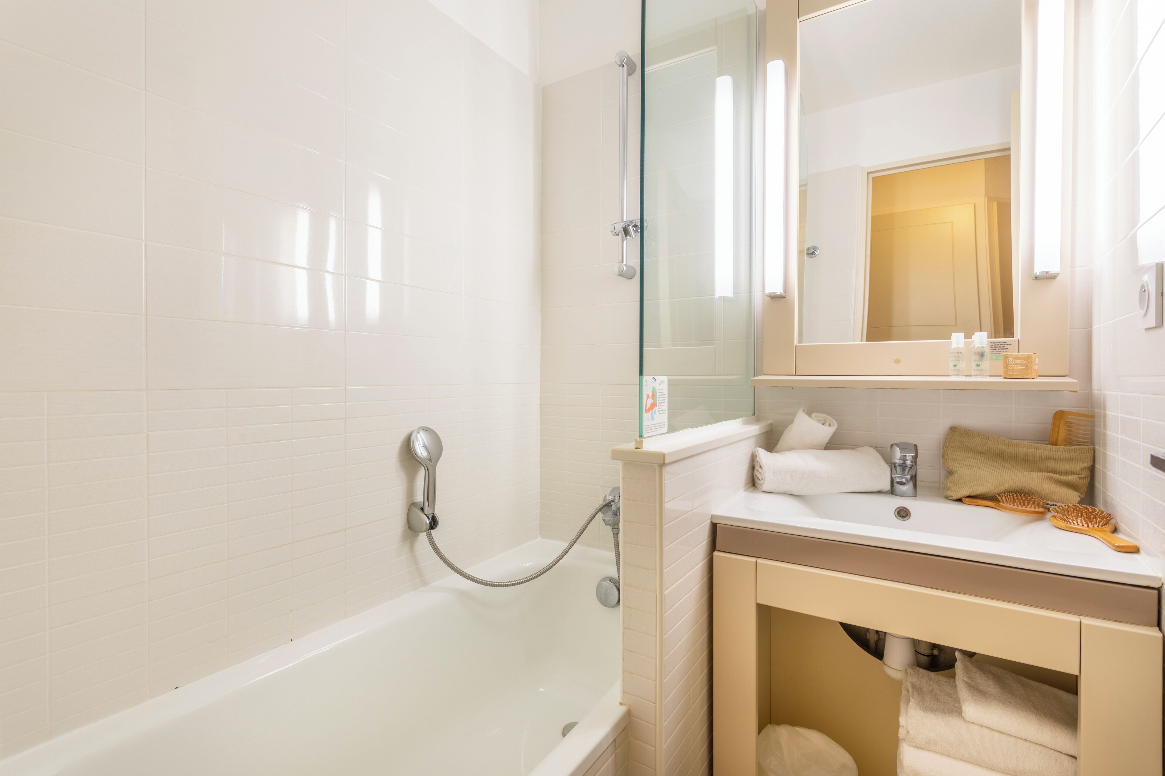 A modern bathroom with a glass-enclosed shower, a white sink with a mirror above it, and a towel rack.