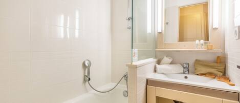 A modern bathroom with a glass-enclosed shower, a white sink with a mirror above it, and a towel rack.