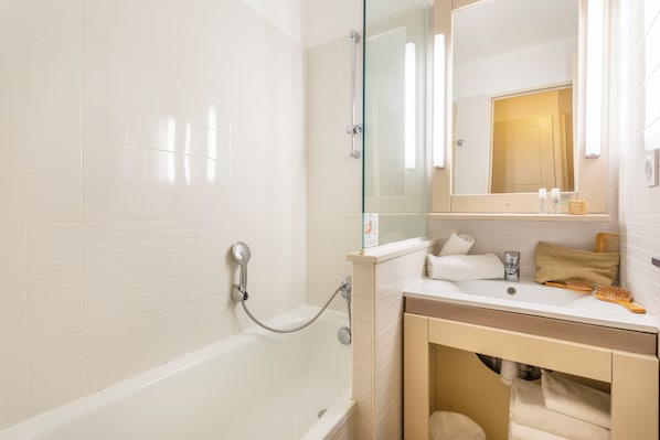 Un baño moderno con ducha de vidrio, un lavabo blanco con un espejo encima y un perchero para toallas.