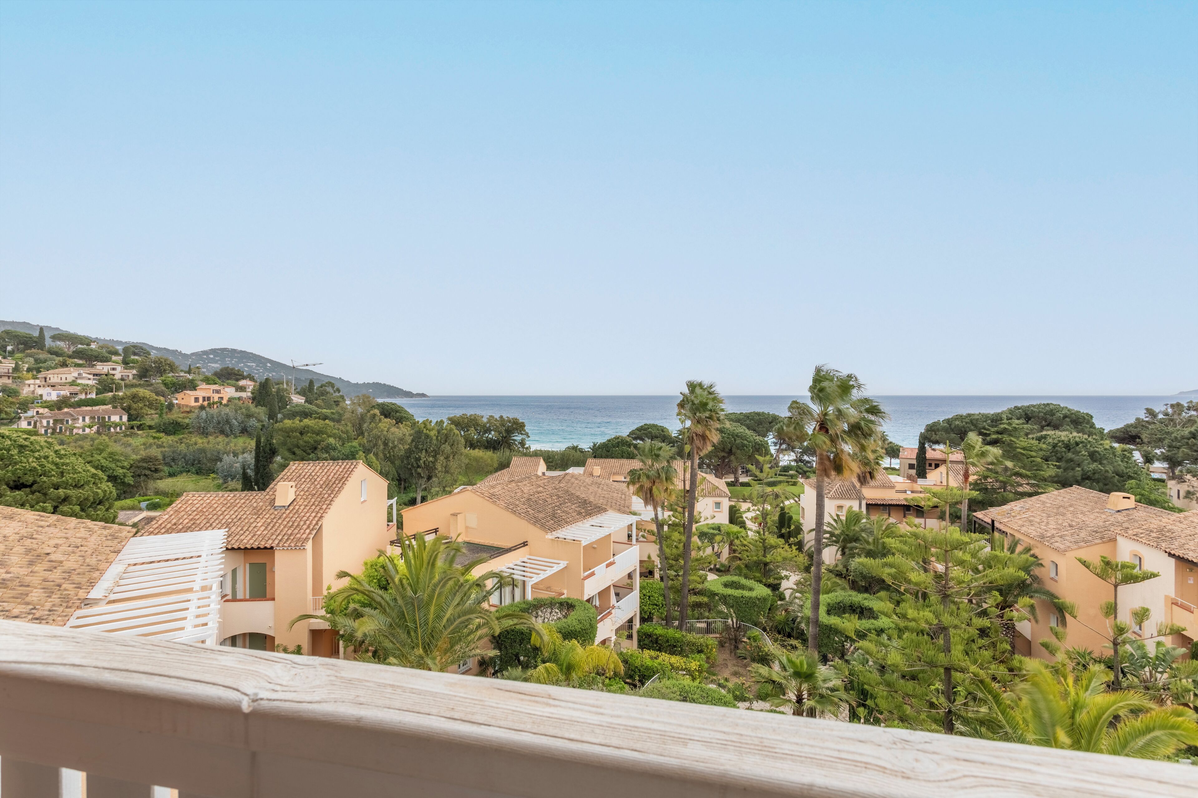 A coastal residential area with terraced houses, palm trees, and a view of the sea.