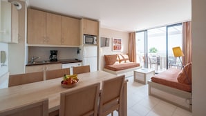 A compact living space with a kitchenette, dining area, and a sofa with a view. - Pierre & Vacances Residence L'Anse de Pramousquier (Le Lavandou)