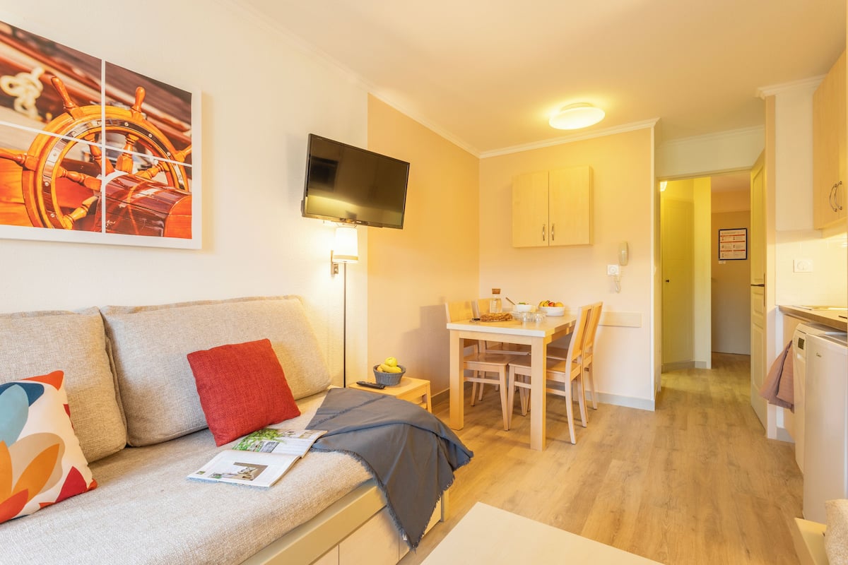 Ein gemütliches Wohnzimmer mit einer Couch, einem Flachbildfernseher und einem Essbereich mit Tisch und Stühlen.