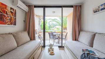 A modern room with a sofa, a small table with a teapot and cups, and a balcony with a table and chairs.