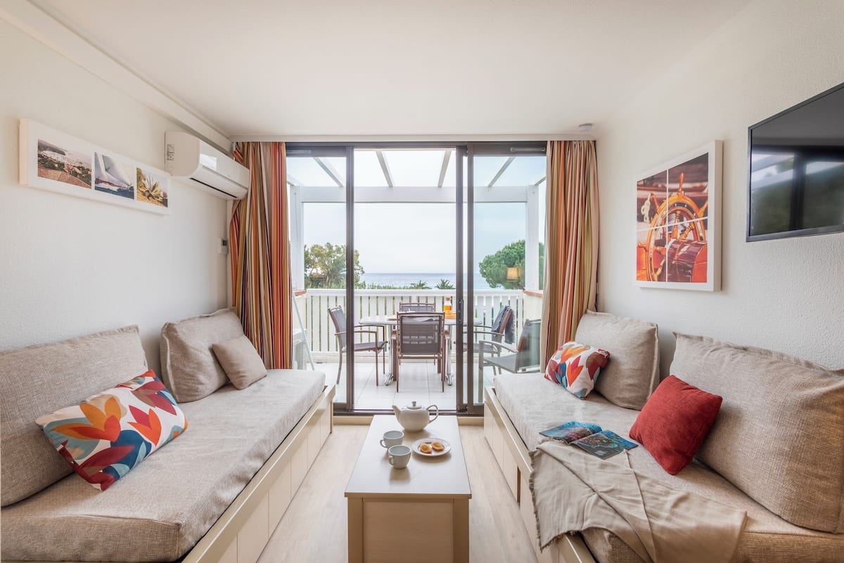 Ein modernes Wohnzimmer mit zwei Sofas, einem Couchtisch und einem Balkon mit Meerblick.