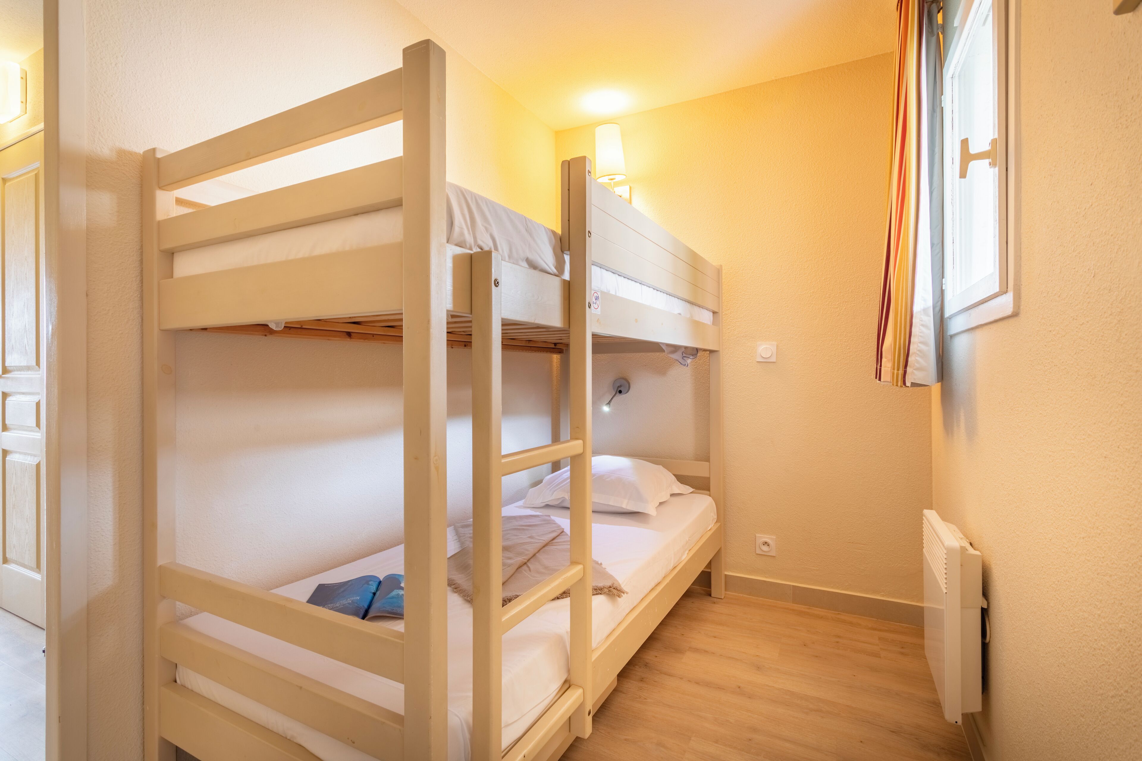 A bunk bed room with a single bedside table, a lamp, and a radiator.