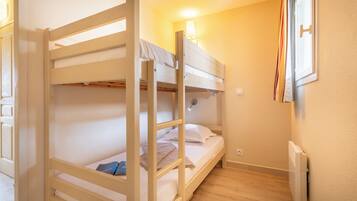 A bunk bed room with a single bedside table, a lamp, and a radiator.