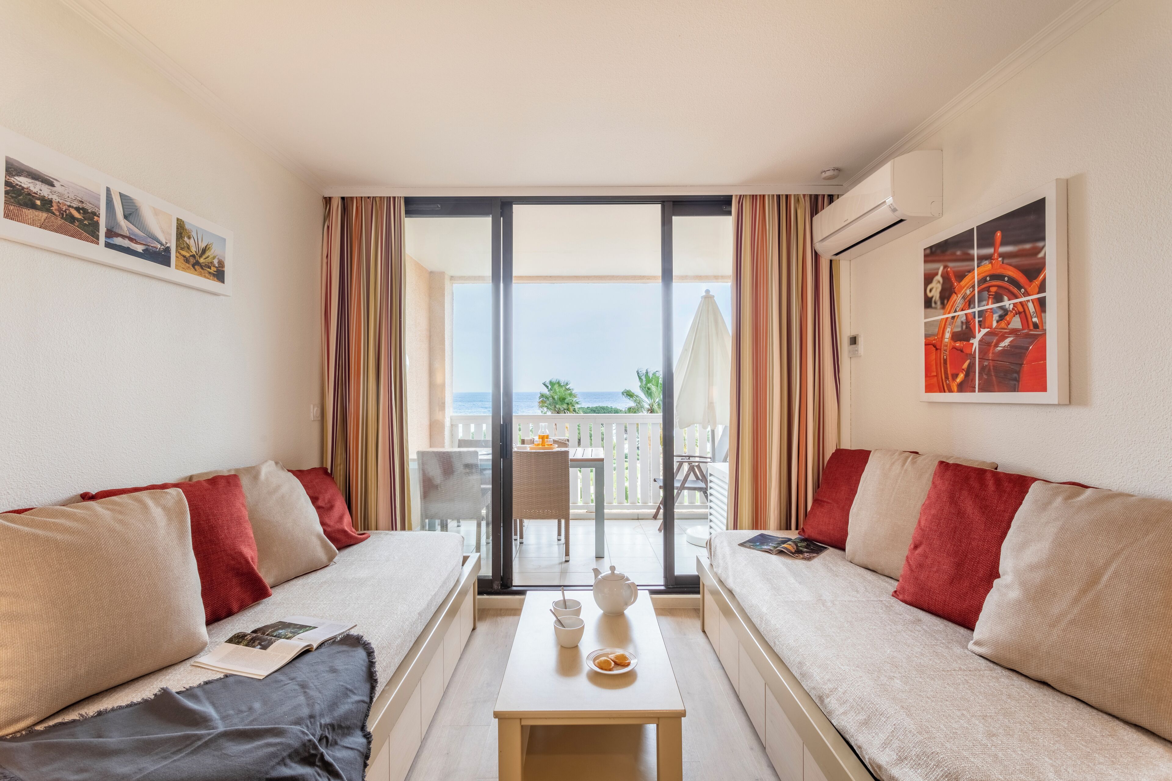 Una camera d'albergo con due divani, un tavolino con teiera e tazze, e un balcone con tavolo e sedie.