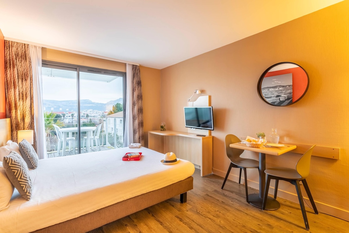 Une chambre d’hôtel comprenant un lit, un bureau avec une télévision, une table à manger avec des chaises et une vue sur la ville.